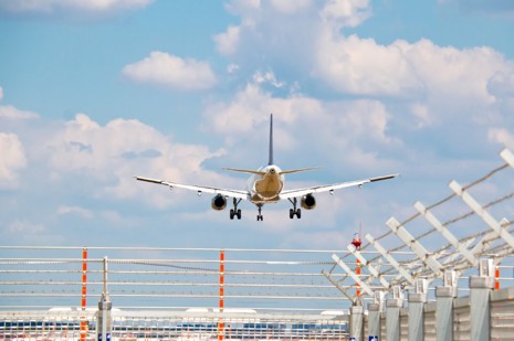 Barbed wired fence with an aircraft landing in the background.jpg