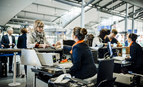 Travellers at an airport checkin counter dropping their luggage and getting boarding passes.jpg