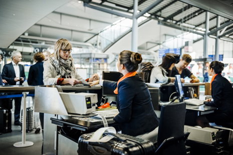 Travellers at an airport checkin counter dropping their luggage and getting boarding passes.jpg