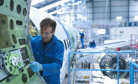 Aircraft engineer fixing a commercial aircraft door inside a hangar
